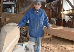 man surrounded by canoes in workshop