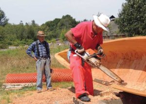 man with chainsaw carving a canoe