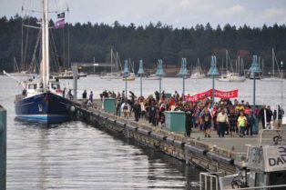 people marching in protest on fishing dock