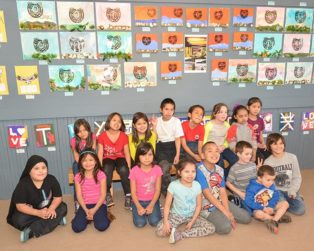 students pose in front of their art