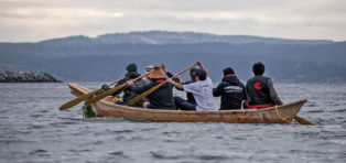 first nations paddling a canoe