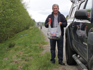 man collecting cans beside highway