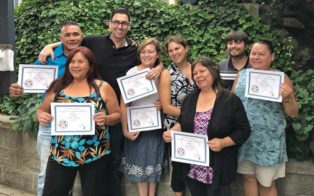 graduates hold up certificates